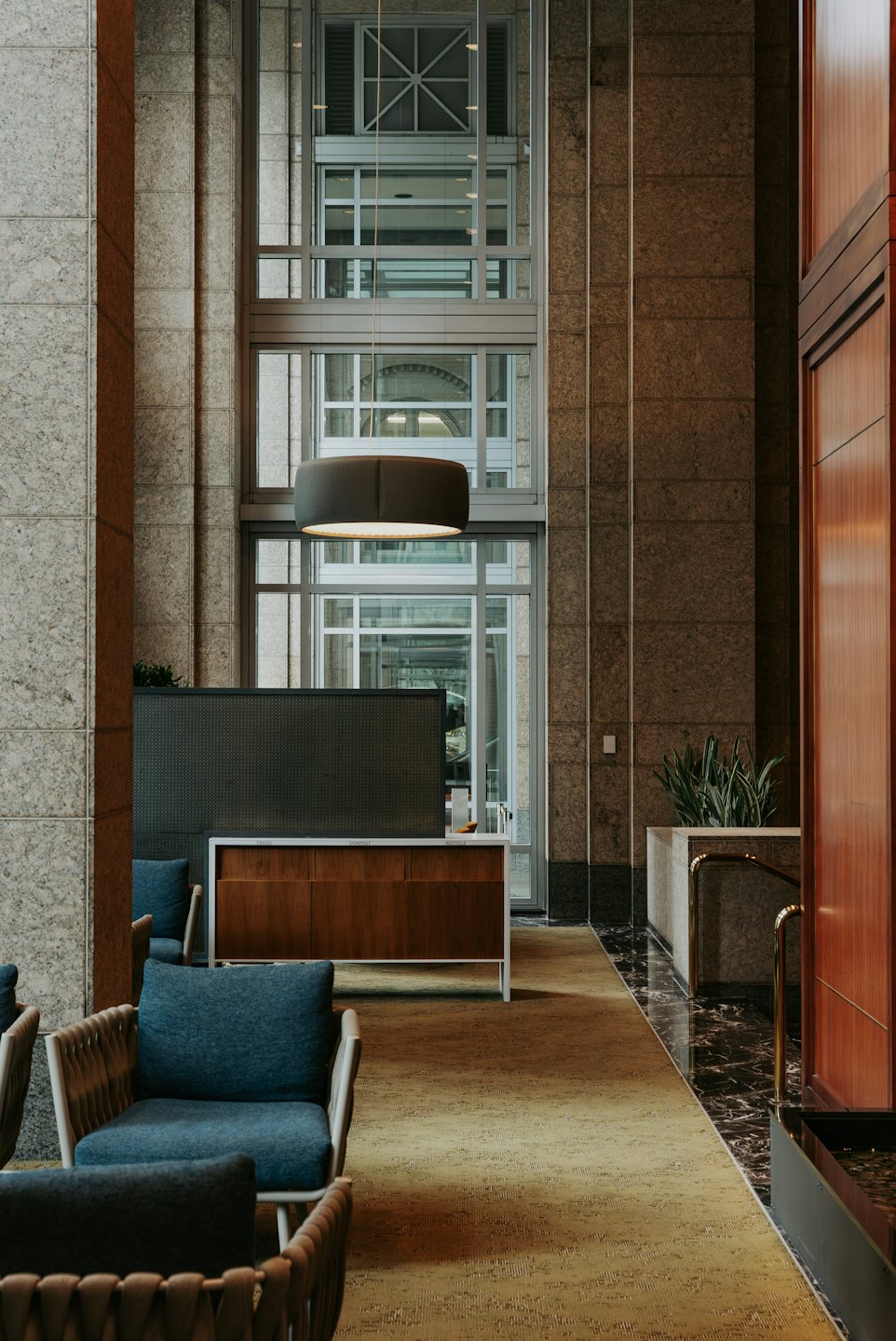Modern office lobby with blue chairs and wooden reception desk.
