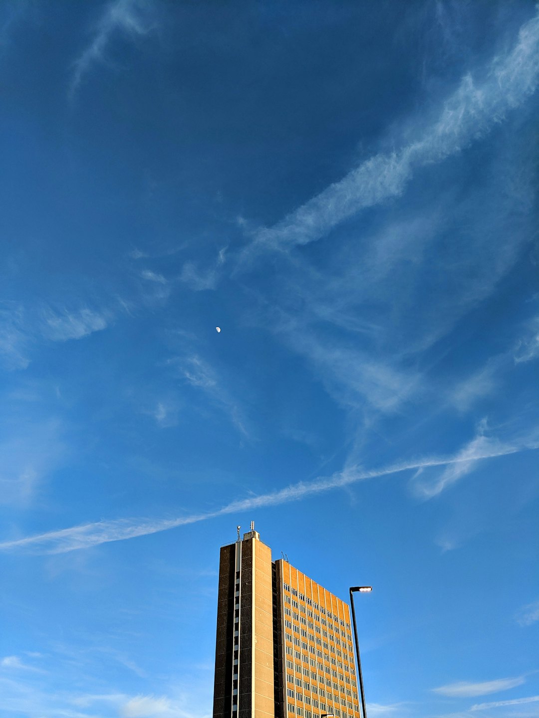 Modern tan corporate building rising into a clear blue sky.