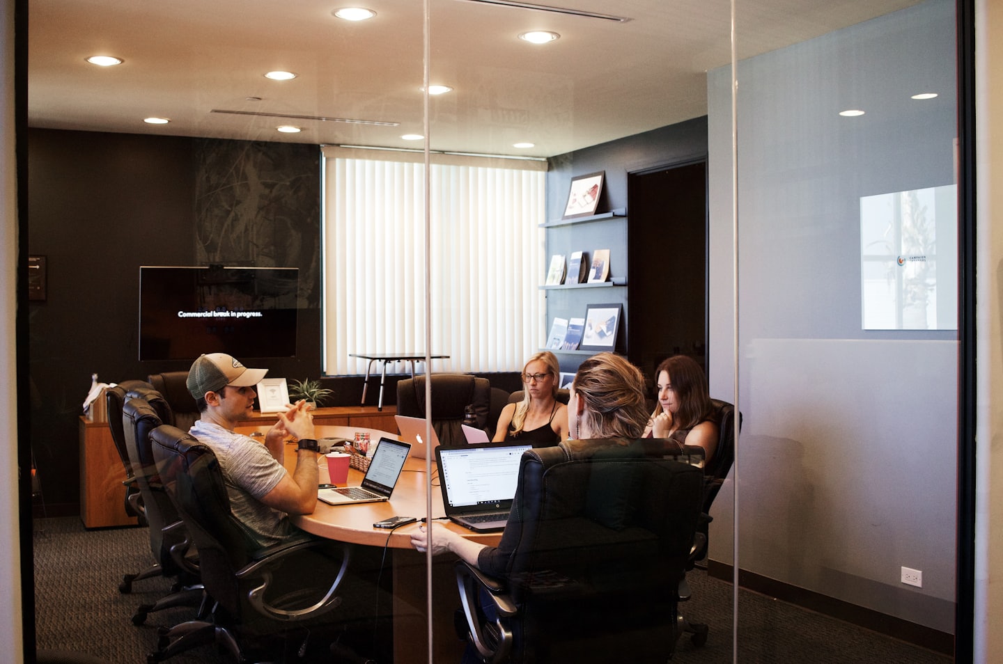 Four professionals discuss work around a conference table.